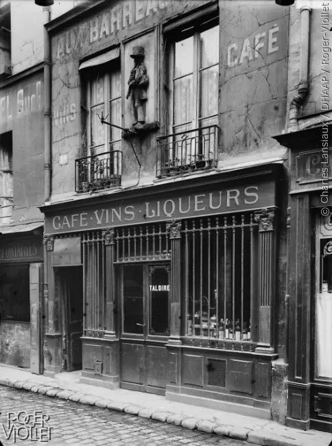 19 rue de Lappe. Au joueur de musette. Façade sur rue, détail de la grille de la boutique et de l’enseigne. 21 septembre 1920. © Charles Lansiaux, DHAAP, Roger-Viollet