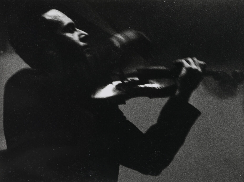 Louis INGIGLIARDI, dit INGI (1915-2008). "Igor OISTRAKH (1931-2021), Violoniste". Prises de vues mars 1961, salle Pleyel avec l'orchestre de chambre de l'ORTF. Tirage argentique 1994 image 18 x 39.8 cm, feuille 24 x 30.3 cm. Oeuvre mise en vente par Vichy Enchères le 2 juin 2025 © C. Darbelet